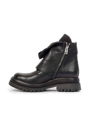 Bottine noire en cuir avec semelle épaisse, fermeture éclair latérale partiellement ouverte et rabat en cuir plié sur le devant.