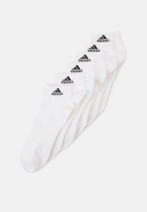 Baltas kokvilnas potītes zeķes ar melnu Adidas logo uz apkakles. Vienkāršs dizains, mīksta tekstūra un sešas pāri sakārtoti rindā.