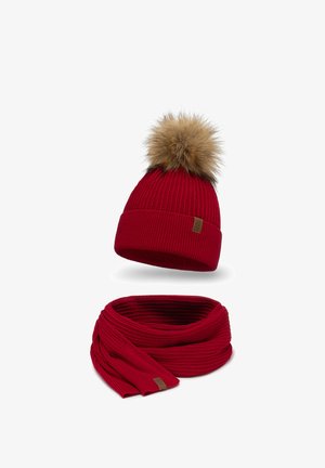 Red knit beanie with a faux fur pom-pom and matching ribbed scarf. Both feature a textured design and a small logo patch.