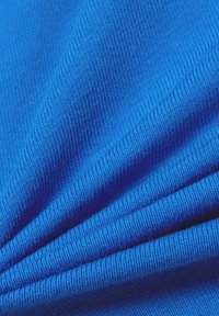 Blue ribbed fabric, showcasing textured lines and smooth surface, folded to highlight its vibrant color and soft, stretchy material.