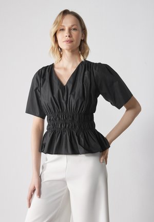 Black peplum top made of cotton with a V-neckline, short puff sleeves, and elastic smocking at the waist. Paired with white trousers.