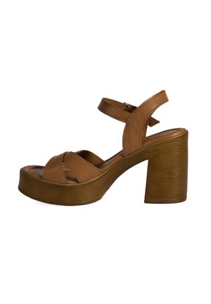 Brown leather platform sandals with crossed straps, ankle strap, and a chunky wooden heel. Smooth texture and pronounced curved shape.