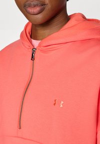 Κοραλλί φούτερ με φερμουάρ και υφή, με μεταλλικό φερμουάρ και διακοσμητικό λογότυπο στο στήθος. Μαλακό, ελαφρύ ύφασμα.