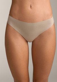 Beżowa, bezszwowa bielizna bikini o gładkiej fakturze i niskim kroju, z szerokim pasem i minimalnym zakryciem z tyłu.