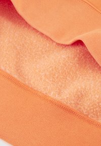 Tela naranja con una textura interior suave y aterciopelada y una capa exterior lisa. Presenta un detalle de dobladillo acanalado, apto para un estilo casual.