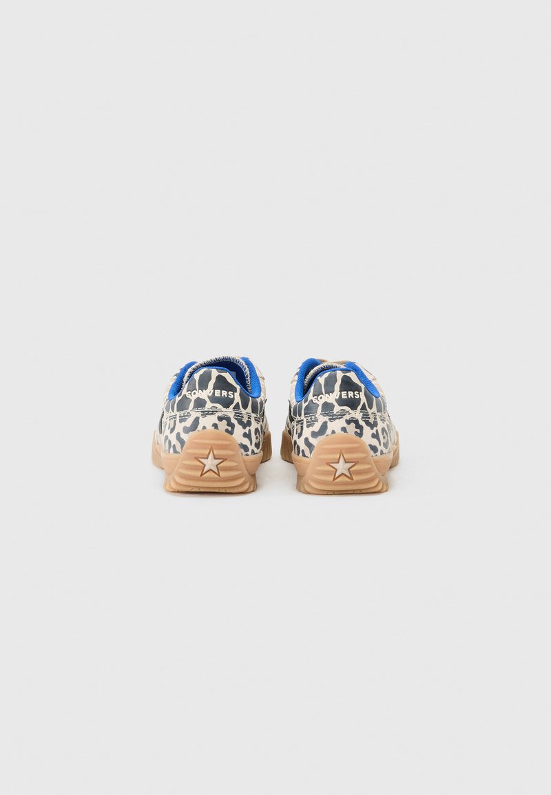 Zapatillas con estampado de leopardo que cuentan con una base beige, detalles en azul y suelas de goma con un diseño de estrella en el talón.