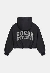 Schwarze, kurz geschnittene Jacke mit Kapuze, versehen mit weißem "GUESS EST. 1981"-Logo in gepunktetem Muster. Elastische Bündchen und Bund, glatter Stoff.
