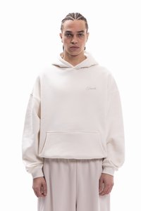 Sweat à capuche surdimensionné de couleur crème avec une poche avant et une broderie discrète "Favela". Texture douce, manches larges et capuche à cordon.
