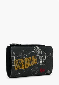 Black fabric wallet with zipper, featuring yellow graffiti-style "DESIGUAL" text and white and red abstract designs on the front.