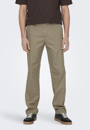 Pantalones caquis con un corte recto, hechos de una tela suave, con un frente plano y trajes para el cinturón, combinados con zapatillas negras.