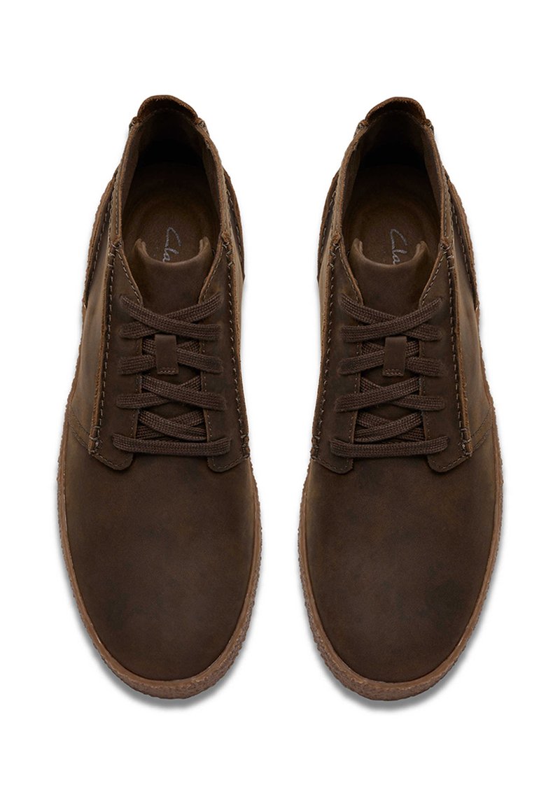 Braune Lederschuhe mit einer glatten Oberfläche, Schnürverschluss und minimalen Nähten. Die Laufsohle ist leicht strukturiert für besseren Halt.