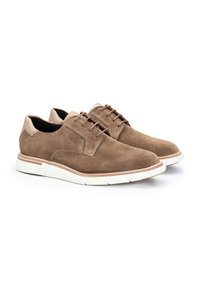 Chaussures en daim marron avec des accents en cuir beige clair, orteils arrondis et semelles en caoutchouc blanches, dotées de lacets marron et de détails de couture.