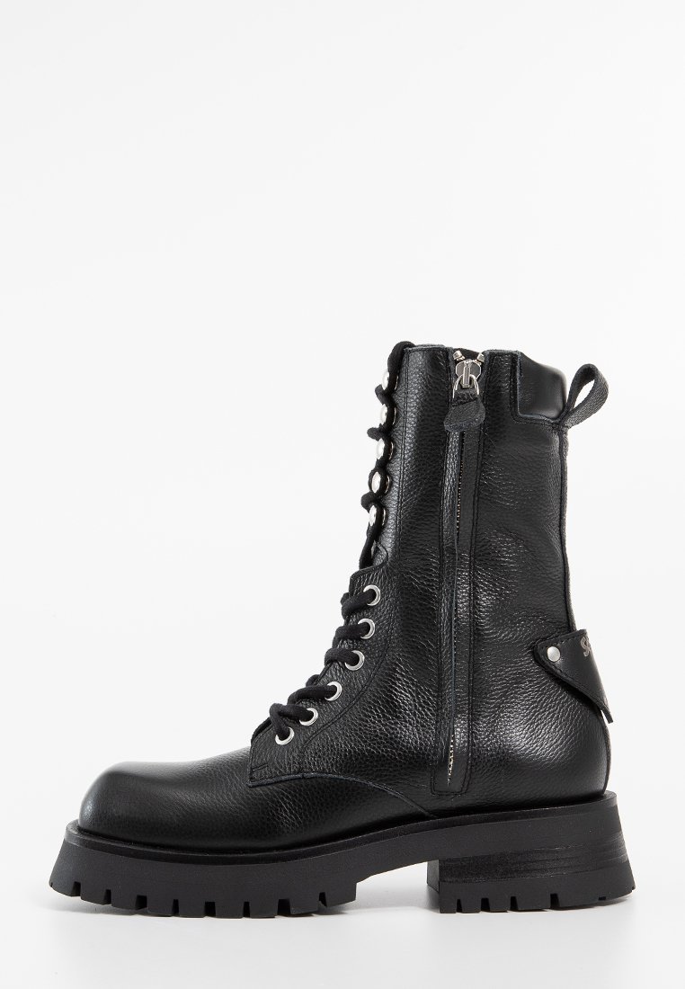 Bottes de combat en cuir noir avec un laçage à l'avant, fermeture éclair sur le côté et finition texturée. Elles possèdent une semelle épaisse et robuste ainsi que des accents de design minimalistes.