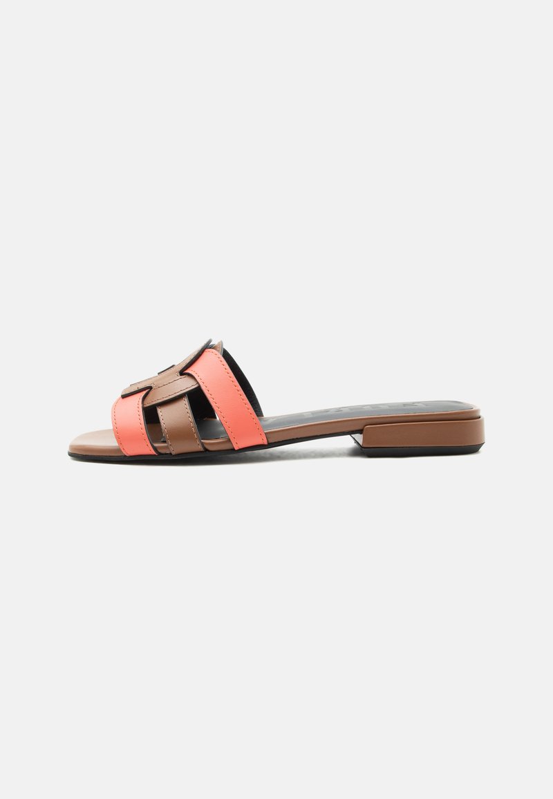 Sandale plate à enfiler avec larges brides en cuir corail et marron et un petit talon carré sur fond blanc.