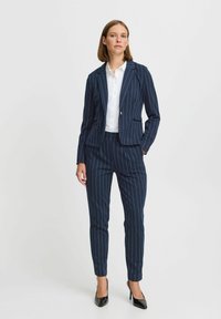 Marint randig kostym med en figursydd blazer och avsmalnande byxor. Tillverkad av mjukt tyg, med en stängning i två knappar och subtila fickdetaljer.