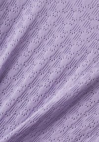 Tissu en maille violet clair avec des trous en œillet diagonaux formant un motif texturé et répétitif ainsi que des plis doux.