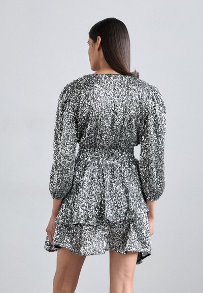 Zilveren paillettenjurk met opgezette mouwen, gelaagd ruchesrok en een getailleerde taille. Glanzende textuur creëert een sprankelend effect.
