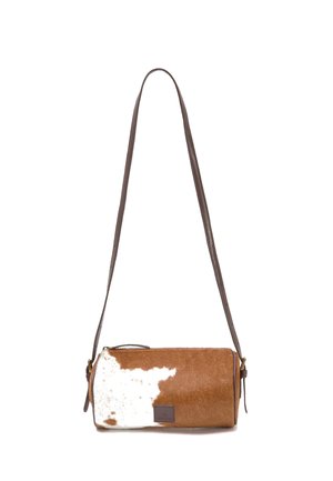 Bolso bandolera cilíndrico de piel de vaca marrón y blanca con una correa larga ajustable de cuero marrón oscuro.