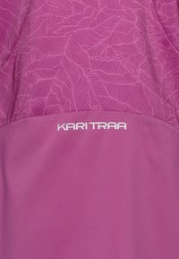 Paarse Kari Traa kledingstuk met een gestructureerd loofpatroon en een glad gedeelte eronder met een logo. Zachte stof met contrasterende ontwerpen.
