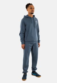 Conjunto de sudadera con capucha y pantalones de chándal en suave tela azul. Incluye un bolsillo tipo canguro, puños de canalé y un discreto detalle de logo en el pecho.