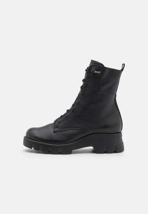 Bottines noires en cuir avec une finition texturée, un design à lacets et une semelle en caoutchouc épaisse avec un motif saillant pour une meilleure adhérence.