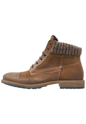 Bottine en cuir marron à cheville avec bord tricoté, lacets à l’avant et semelle texturée, conçue pour un usage décontracté ou extérieur.