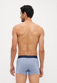 Boxers pour hommes en tissu bleu clair avec une taille couleur bleu marine. Le design présente une coupe ajustée et une texture lisse.