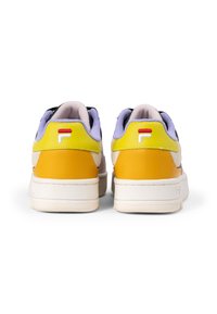Sneaker che presentano una combinazione di pelle e tessuto giallo, nero e lavanda. La parte posteriore mostra un dettaglio del logo e suole testurizzate.