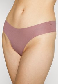 Mauve stringondergoed met een naadloos ontwerp. Gemaakt van zachte, rekbare stof met een brede tailleband en een minimalistische snit.