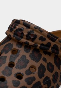 Καφέ παπούτσι κλογκ με μαύρο και σκούρο κόκκινο λεοπαρ σχέδιο και οπές αερισμού, με ρυθμιζόμενο λουράκι στο πάνω μέρος.