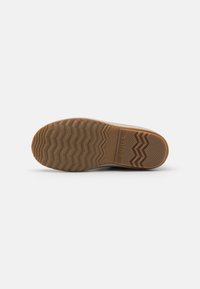 Suela de goma de un zapato Sorel con patrones de tracción de zigzag y ondas profundas, presentada sobre un fondo blanco.