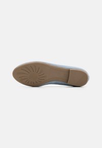 Chaussure bleu clair avec un matériau supérieur doux et une semelle en caoutchouc beige à motifs, dotée d'un bout arrondi et de détails de design minimalistes.