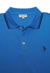 Polo bleu en tissu texturé, avec un col à rayures noires, deux boutons et un petit logo brodé sur la poitrine.