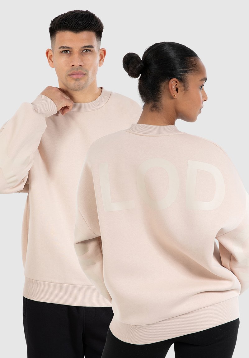 Sweat-shirt rose clair avec des poignets et un col côtelés, comportant un grand graphique "LOD" ton sur ton au dos. Tissu doux et texturé.