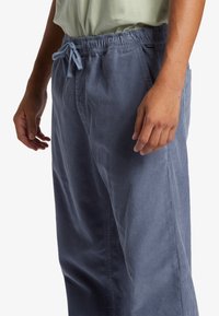 Light blue corduroy pants with an elastic waistband and drawstring, featuring side pockets and a straight leg design.