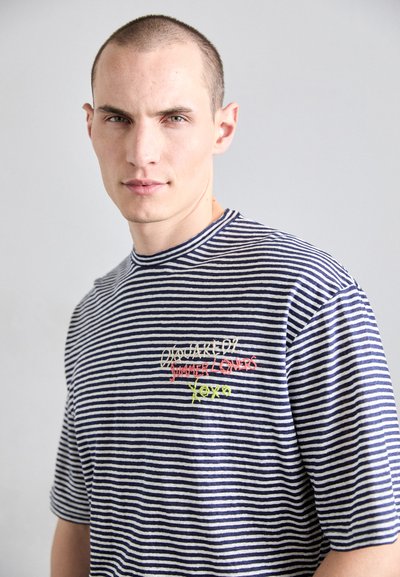 Tricou scurt cu mânecă, cu dungi navy și alb, având brodat un text colorat: "Iubitorii verii" cu accente roșii, galbene și verzi.