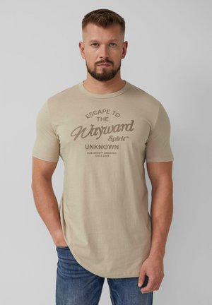 Beżowy t-shirt z krótkim rękawem z okrągłym dekoltem oraz grafiką w brązowym tekście, zestawiony z niebieskimi dżinsami.
