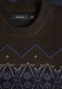 Brun stickad tröja med geometriska mönster i blått och krämfärgat. Har en ribbad rund halsringning och texturerad tyg. Lapp synlig.