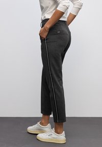 Szare dresy o wąskim kroju, z białym paskiem po boku i elastycznym paskiem w talii. Wykonane z miękkiego materiału, idealne na codzienne noszenie.