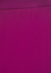 Fuchsia stof met een gestructureerd oppervlak dat fijne horizontale lijnen vert toont en een gladde bovenrand heeft, geschikt voor kleding of stoffering.