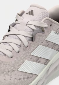 Αθλητικό παπούτσι σε ανοιχτό ροζ με επάνω μέρος από υφή διχτυού, λευκές λεπτομέρειες, λογότυπο με τρεις ρίγες και επίπεδα κορδόνια. Διαθέτει σχεδιασμό με μαλακή, αναπαυτική σόλα.