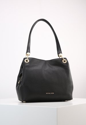 Sac à main en cuir noir texturé Michael Kors avec des ferrures dorées et doubles anses d’épaule sur un socle blanc contre un fond clair.