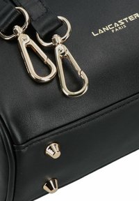 Borsa a tracolla in pelle nera con dettagli in oro, dotata di due attacchi a clip e tre borchie a forma di cono sulla base per un tocco in più.
