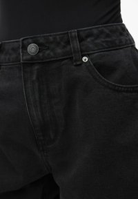 Jeans in denim nero con finitura testurizzata, dotati di chiusura con bottone metallico, passanti per cintura e un design di tasche classico.
