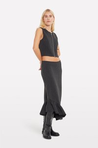 Set din două piese, cu model ribonat, de culoare neagră, care include un top fără mâneci cu fermoar în față și o fustă lungă cu margine volanată. Textură netedă pe întreaga suprafață.