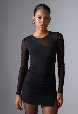 Robe noire à manches longues en mesh transparent, corsage ajusté et mini-jupe. Présente un col rond et une fente sur le côté.