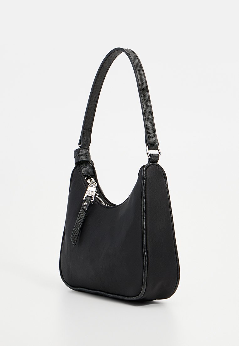Sac à main noir en cuir lisse avec une forme courbe. Il dispose d'une seule bandoulière et d'une fermeture éclair avec des accents en métal argenté.
