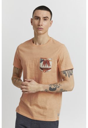 Tricou cu mânecă scurtă, cu guler rotund, de culoare portocalie deschisă, dotat cu un buzunar din material cu model de frunze în nuanțe pământii. Material din amestec de bumbac.