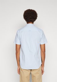 Short-sleeve checkered shirt in light blue and white, cotton fabric, tailored fit, features a back yoke and subtle curved hem.