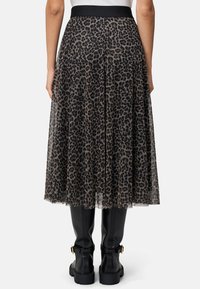 Midikjole med leopardmønster, der har et gennemsigtigt materiale, elastisk sort talje og plisseret design, kombineret med knæhøje sorte støvler.